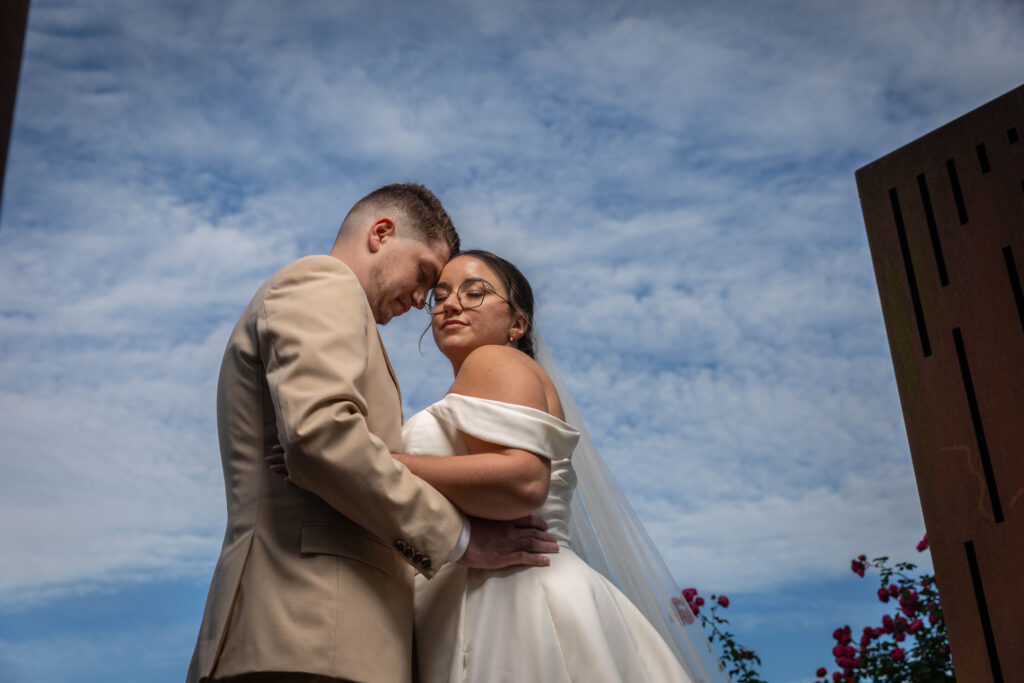 couple de jeune marier qui s'enlace devant un ciel peux nuageux en aprem tête contre tète